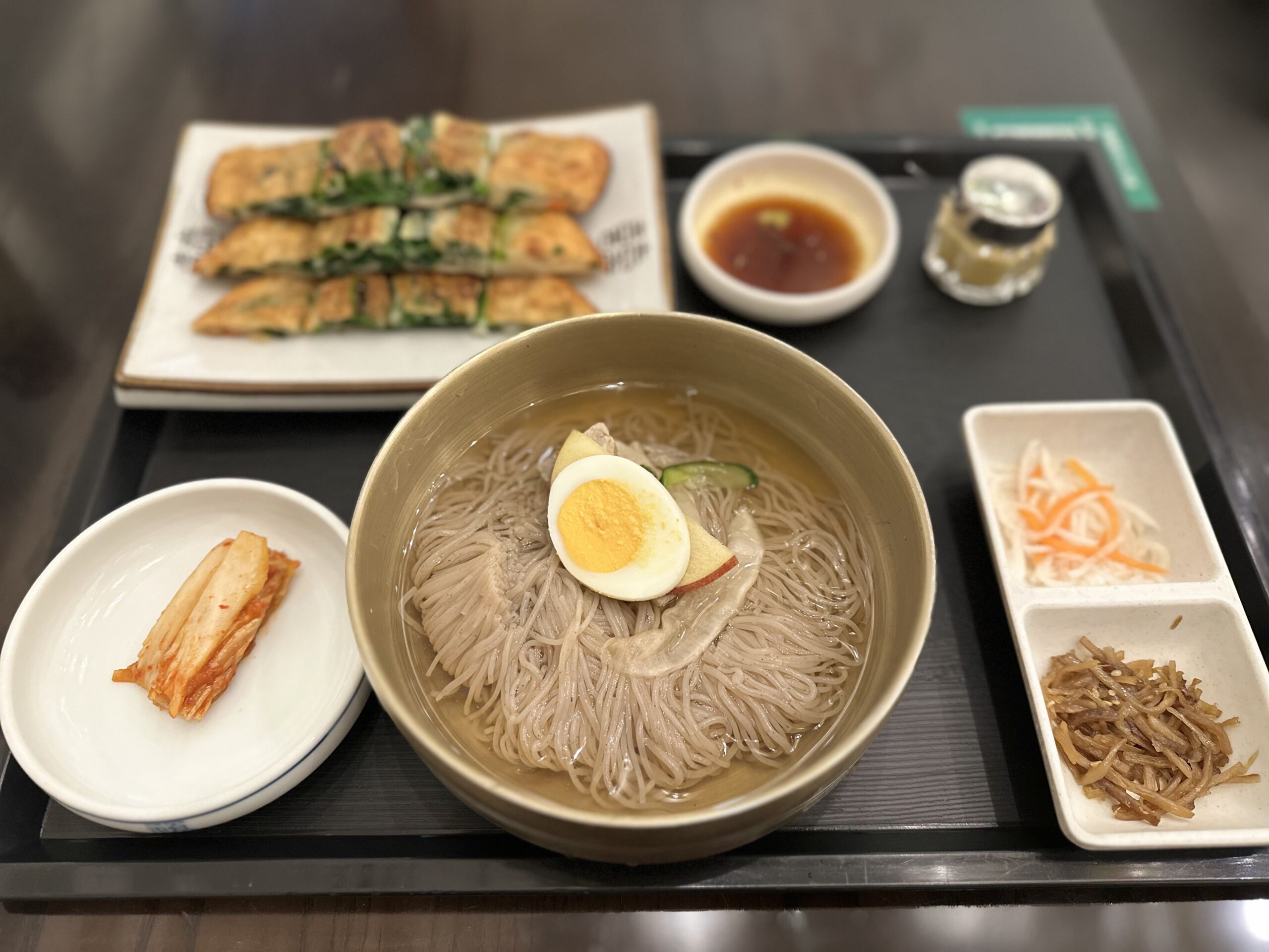 名古屋栄の妻家房の冷麺とチヂミのランチセット。りんごがトッピングされており、小鉢とチヂミが添えられている。