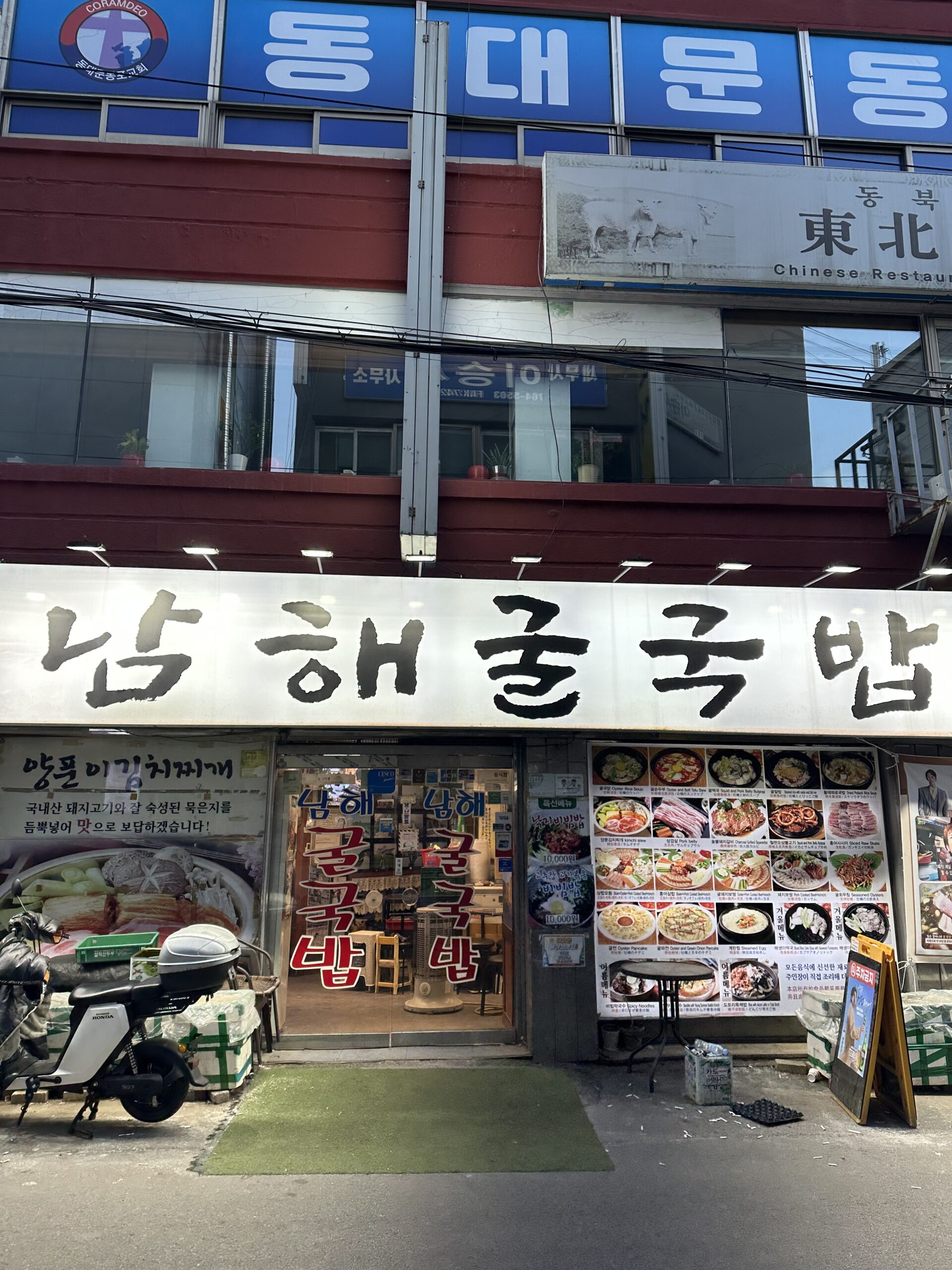 韓国ソウル東大門にある南海牡蠣クッパの外観。青い看板にハングルで「南海牡蠣クッパ」と書かれている。