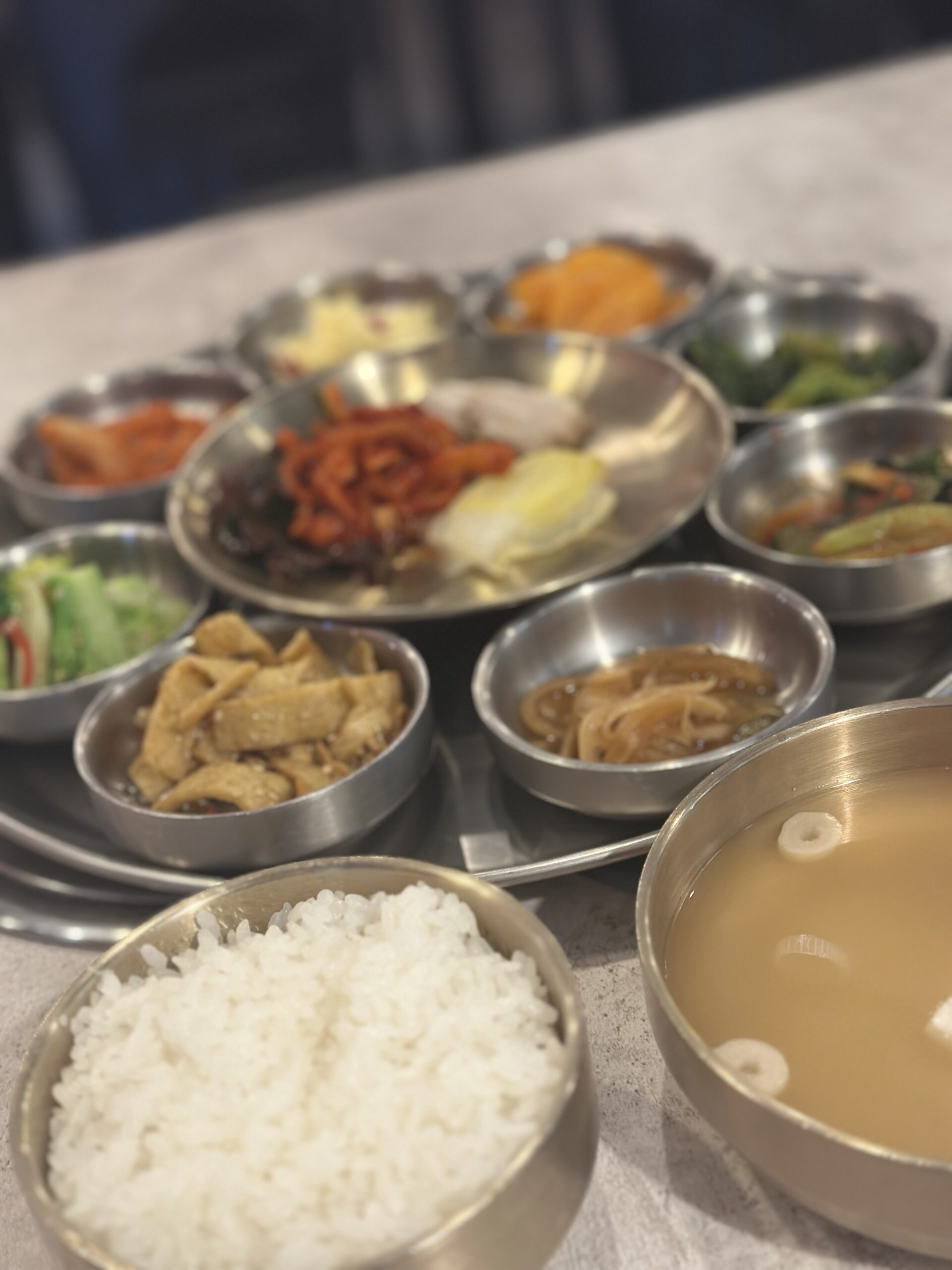 新大久保キサ食堂新大久保店のチュックミ炒め定食。小鉢のおかずやポッサム、ご飯、スープが並ぶ韓国定食